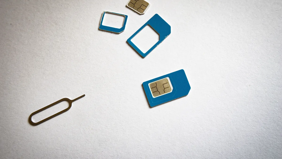 SIM cards and a SIM ejector tool on a white surface