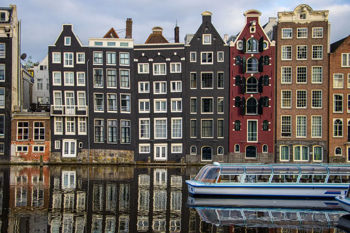 Canal houses and a tour boat in Amsterdam, Netherlands
