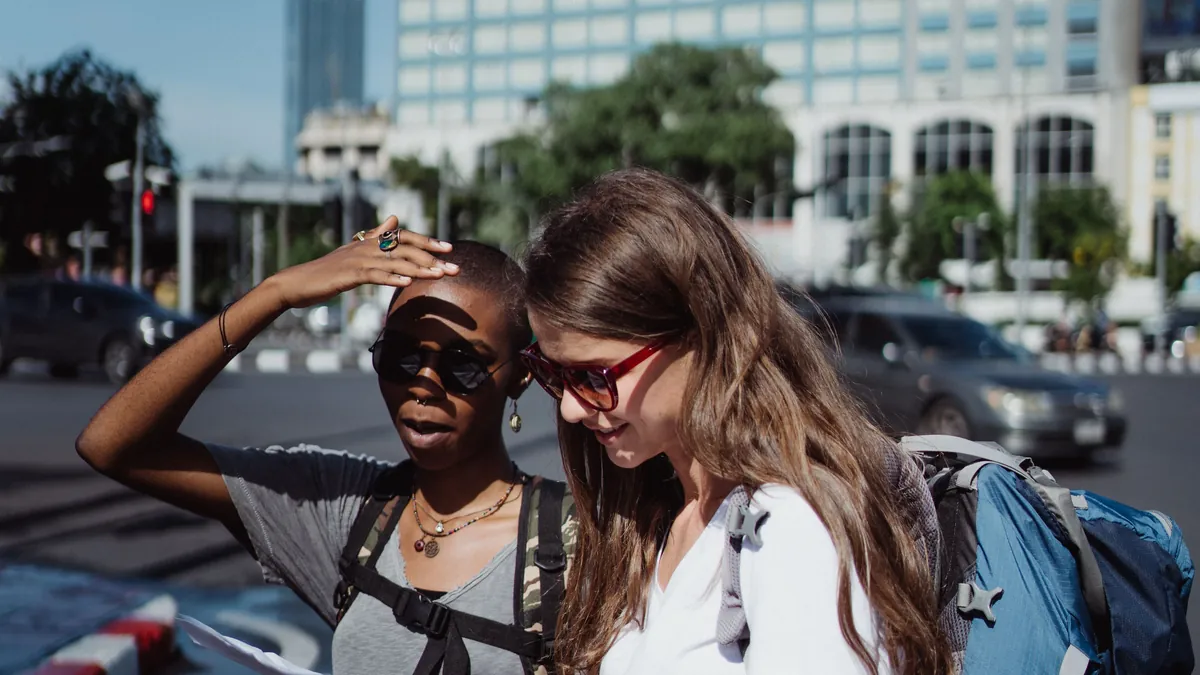 Two travellers with backpacks checking directions in a city
