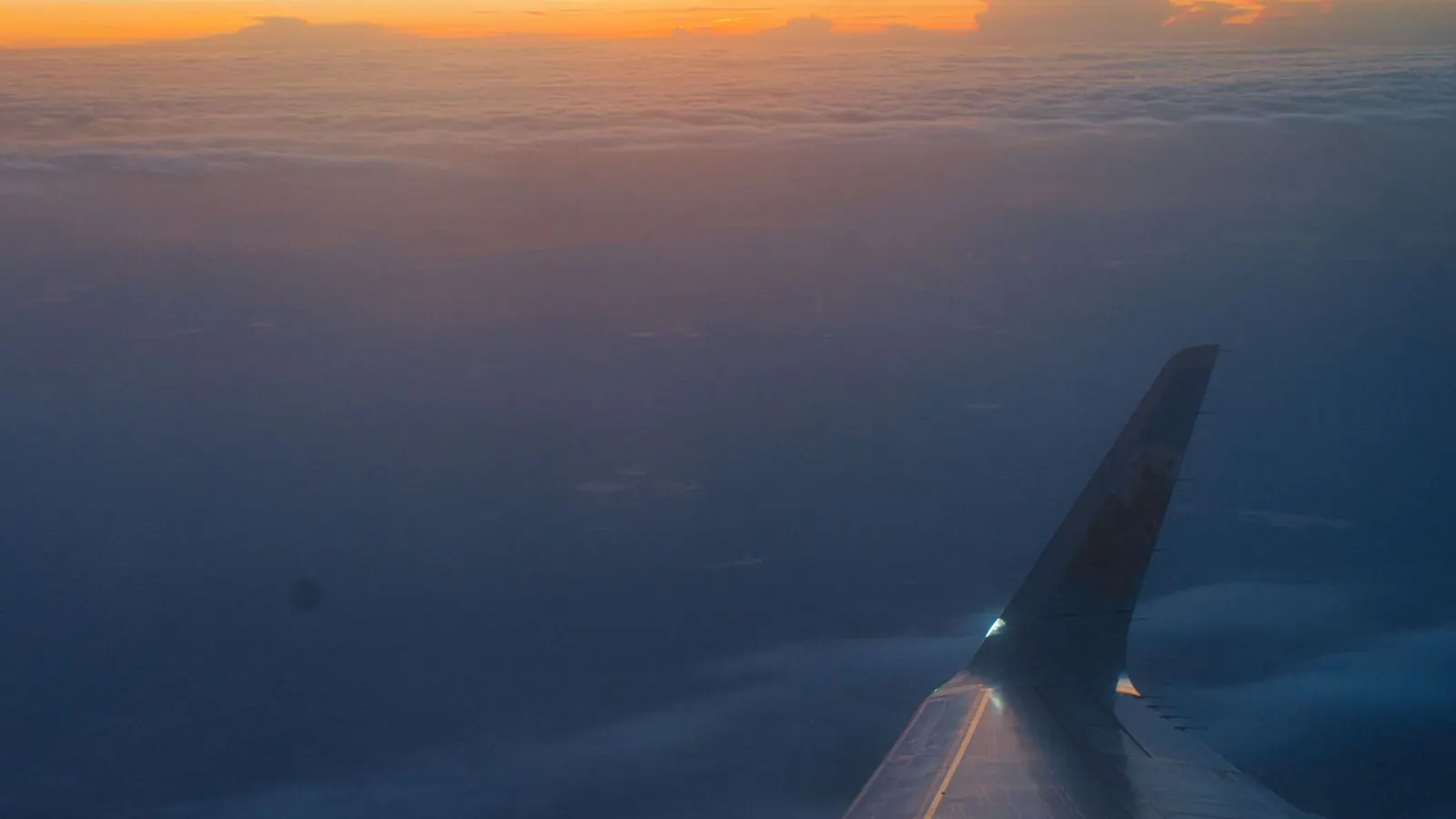 Aeroplane wing above the clouds at sunrise